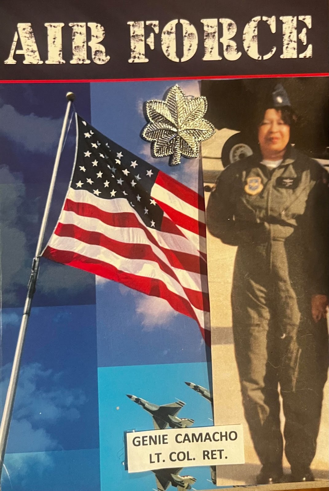 Photo of Grand Marshall Genie Camacho in US Air Force Uniform next to a US Flag