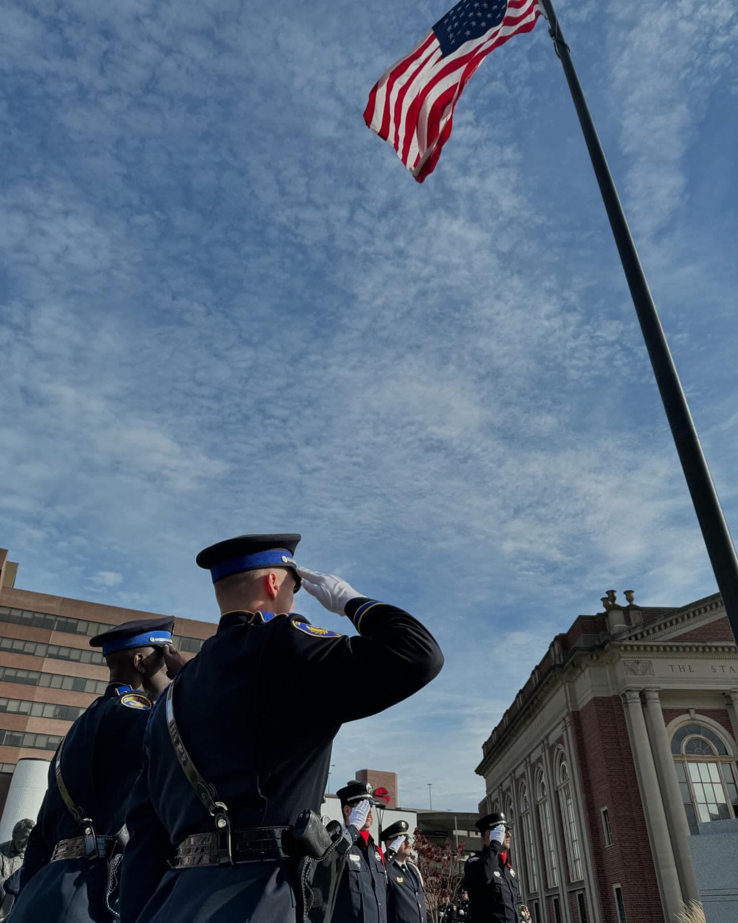 Members of the Stamford Police and Fire Departments salute the US flag